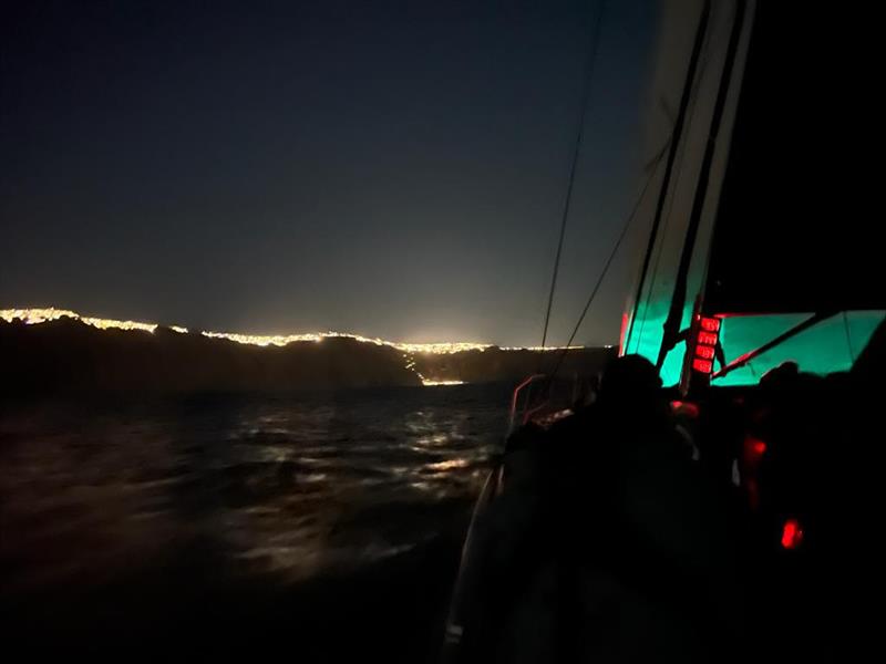 A dramatic night photo of the approach to Santorini, with lights of the town on the cliffs above the pitch-black caldera - 2022 Aegean 600 Race day 2 photo copyright Offshore Racing Congress taken at Hellenic Offshore Racing Club and featuring the ORC class