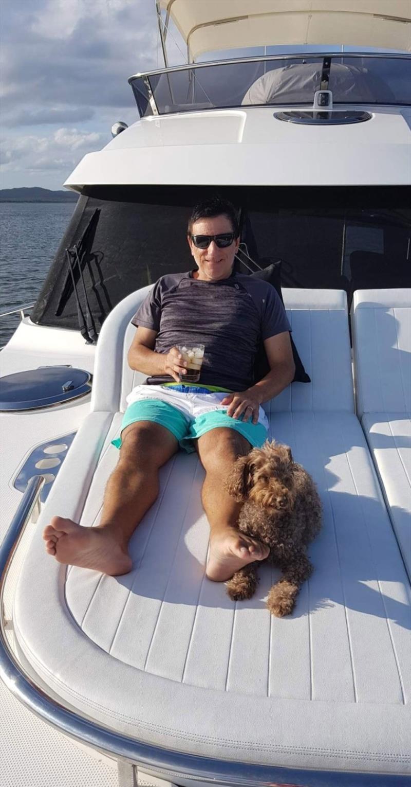 Tony Borgia kicks back on the foredeck with his first mate Grover photo copyright Riviera Australia taken at  and featuring the Power boat class