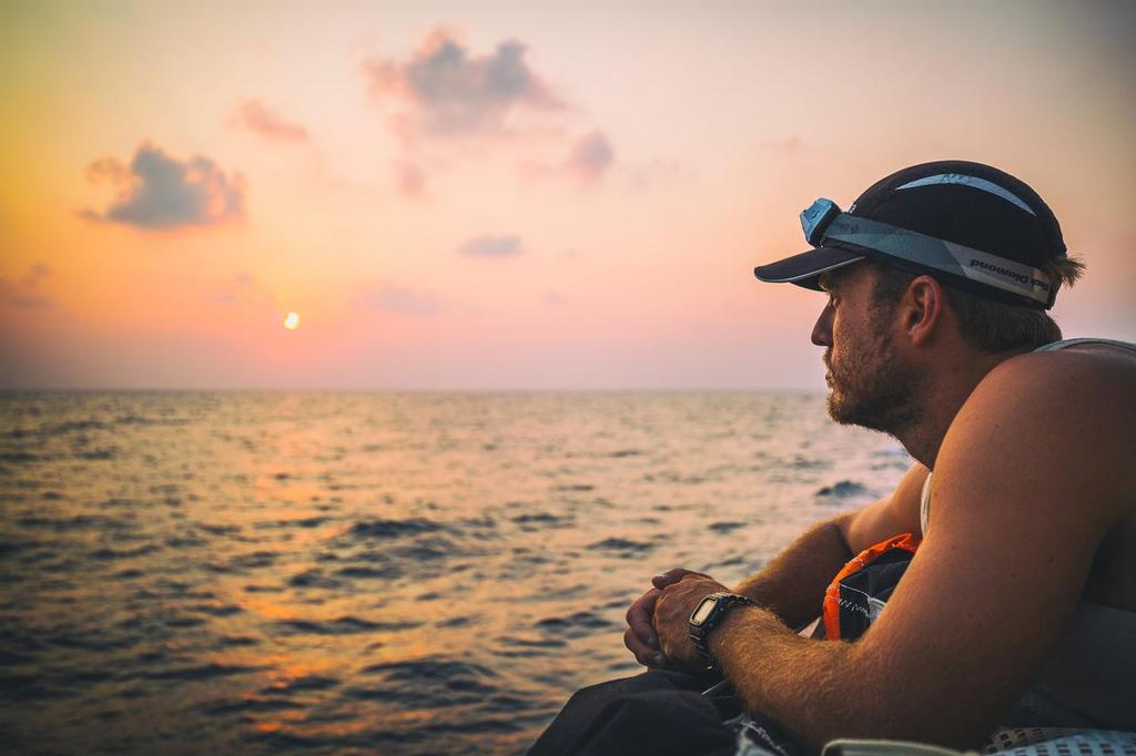 December 9, 2014. Leg 2 onboard Team Alvimedica. DAY 20. A good night of upwind sailing sees the sun rise in the Gulf, firmly in 4th place, having passed MAPFRE in the dark. About 1000 miles until the Straits of Hormuz. Nick Dana taking a breather to look out over the Gulf at sunrise. ©  Amory Ross / Team Alvimedica