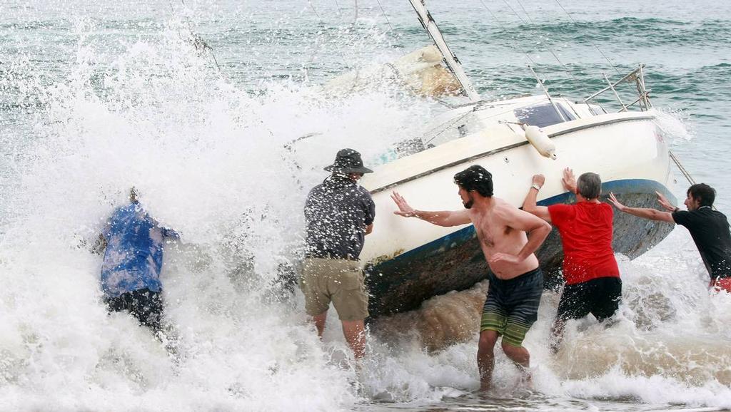 A group of bystanders attempt, unsuccessfully, to manoeuvre the yacht back into the water at Stanwell Park Beach on Sunday. photo copyright Sylvia Liber taken at  and featuring the  class