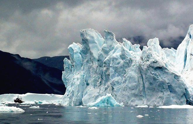 A huge iceberg looms over the 82-foot long M/V Viking Madsalex in Sermilink Fjord. © Alexander Korabiev