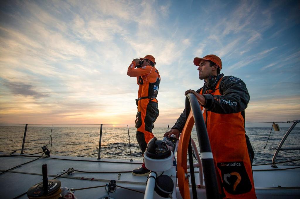 October, 2014. Leg 1 onboard Team Alvimedica. Day 3. After sailing through a front of rough weather overnight, it's a tired but more pleasant race down the African coast towards the Canary Islands. Mark Towill and Will Oxley work together to keep the boat moving. Mark eeks every ounce of speed out of a dying breeze while Will keeps a lookout for more wind on the horizon. ©  Amory Ross / Team Alvimedica