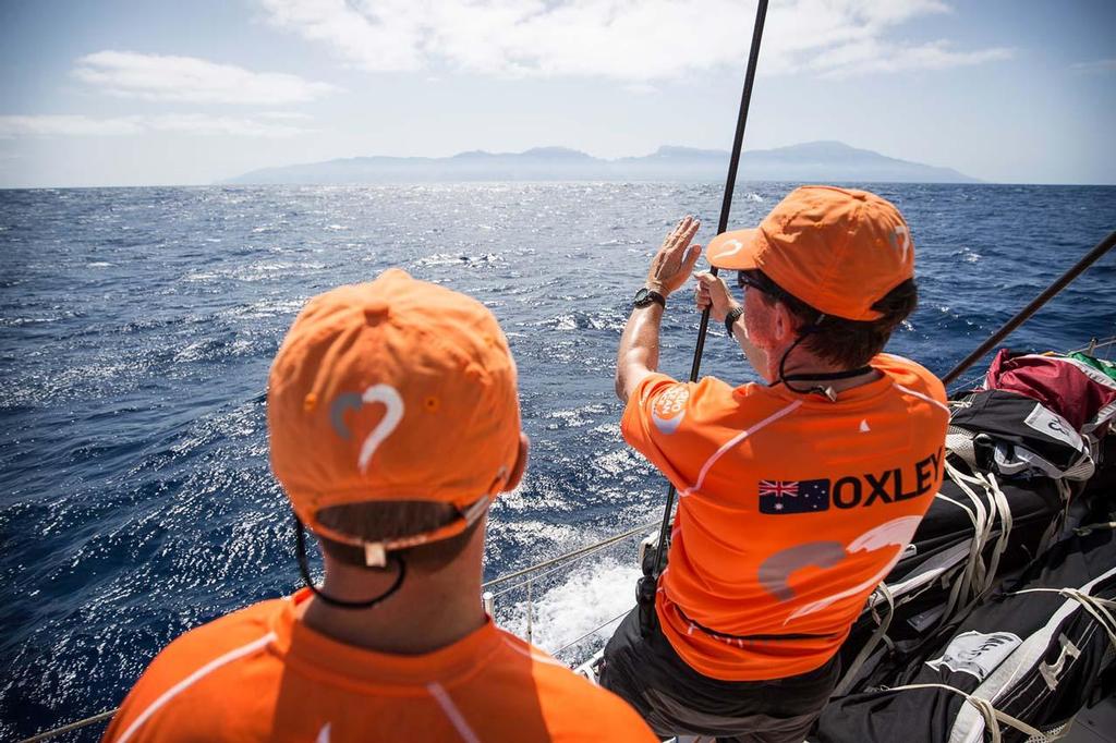 Navigator Will Oxley talks geographical weather with Alberto Bolzan, as Santa Antao--the Cape Verdes island in the distance--plays a large role in the timing of Team Alvimedica's eventual turn south. ©  Amory Ross / Team Alvimedica