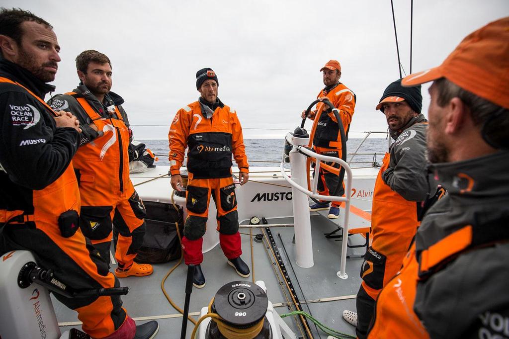 Volvo Ocean Race - October, 2014. Leg 1 onboard Team Alvimedica. Day 19. Temps drop abruptly for the beginning of Day 19, as the fleet sails due south looking for strong westerly winds to turn for Cape Town. A watch change typically involves a debrief from the previous four hours, helping the next watch prepare for their next four. photo copyright  Amory Ross / Team Alvimedica taken at  and featuring the  class