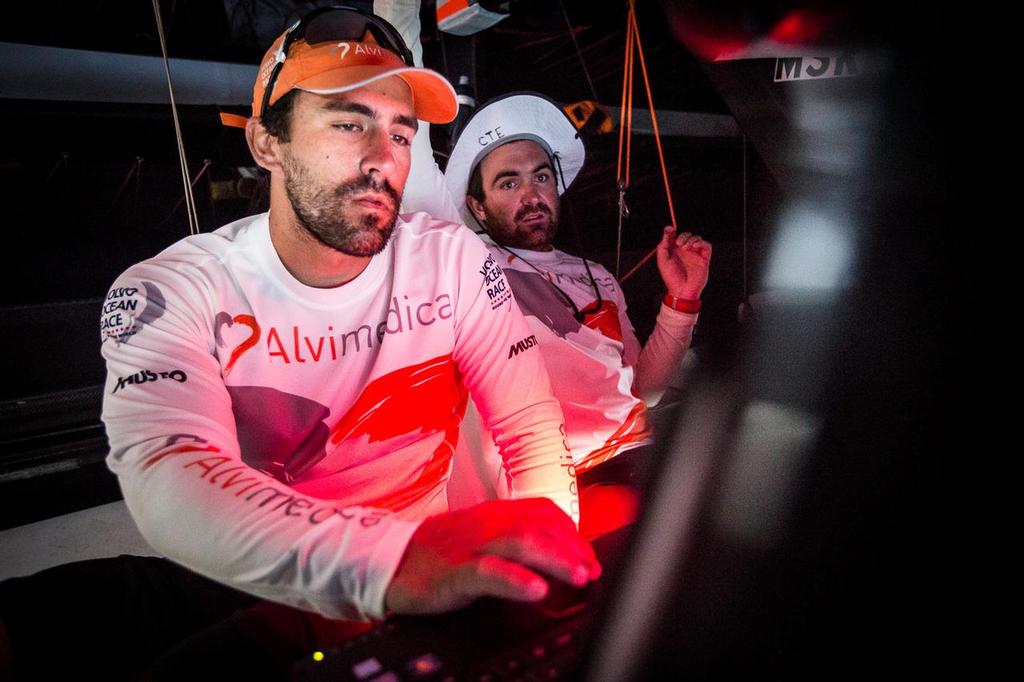 January 18, 2015. Day 15 of Leg 3 to Sanya, onboard Team Alvimedica. Windy upwind conditions make the last 100 miles to Sumatera and the corner of the Malacca Strait rough and wet. Mark Towill (L) and Charlie Enright (R) at work in the nav station, discussing the options for entrance to the Malacca Strait. ©  Amory Ross / Team Alvimedica
