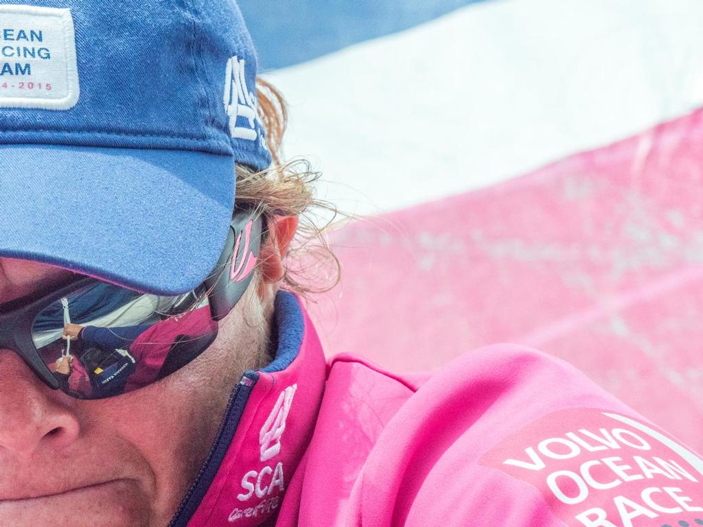 Leg 1 onboard Team SCA. Sally Barkow pulls the strop of the sail bag tight, as seen in the reflection of her sun glasses. © Corinna Halloran / Team SCA