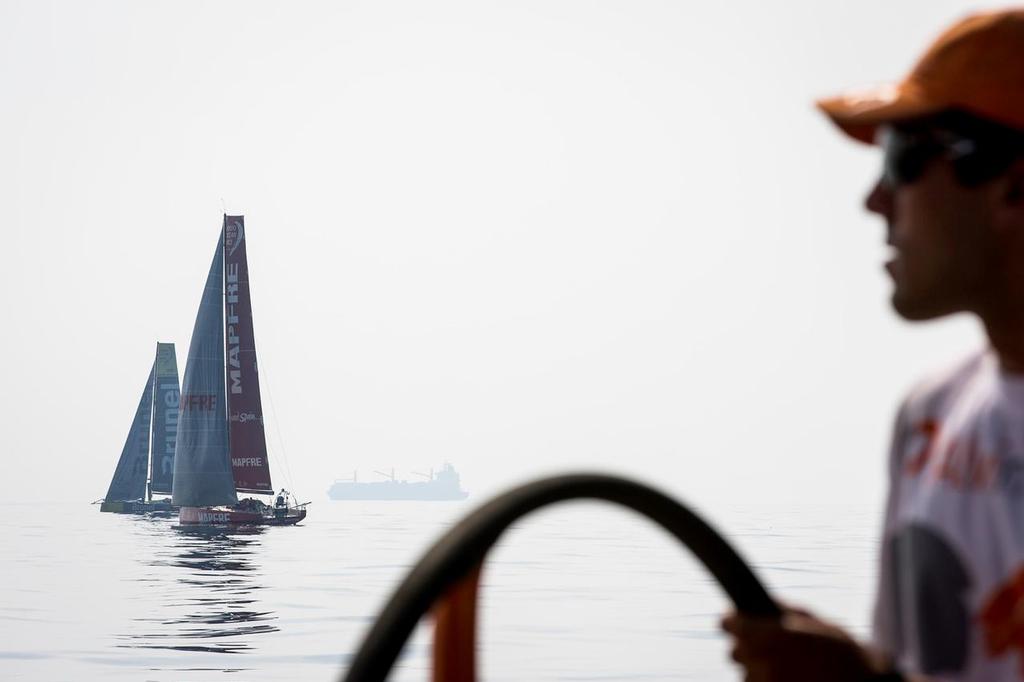 January 4, 2015. Leg 3 onboard Team Alvimedica. Day 1. Winds dissipate as the temperatures rise in the Straits of Hormuz. Mark Towill helming in zero wind, with Mapfre and Brunel drifting nearby. ©  Amory Ross / Team Alvimedica