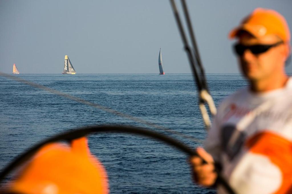 January 5, 2015. Leg 3 onboard Team Alvimedica. Day 2. The close sailing east through the Straits of Hormuz continues, and the fleet enters the Gulf of Oman on it’s way towards India. Ryan Houston on the helm in light and variable sailing conditions, with Brunel, MAPFRE and Abu Dhabi Ocean Racing close behind. ©  Amory Ross / Team Alvimedica