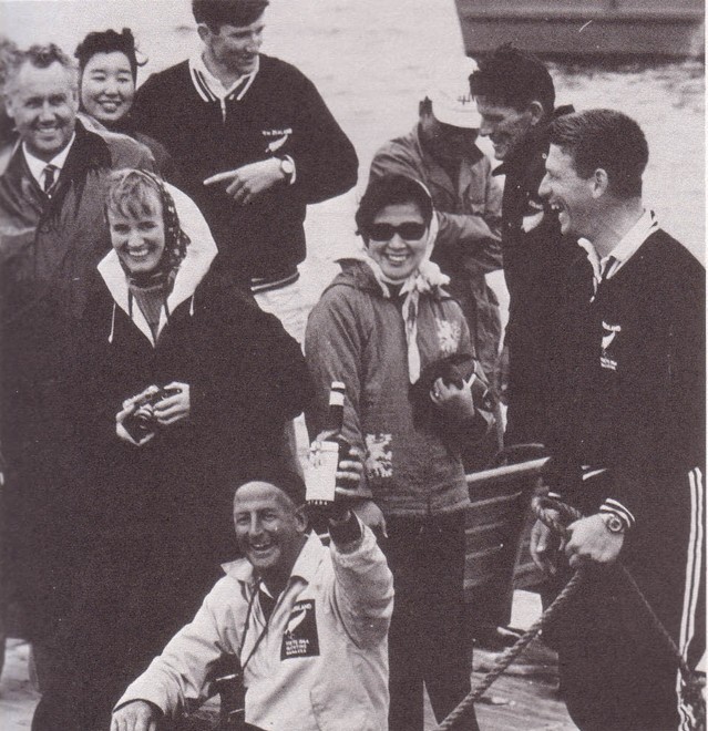 Don St Clair Brown (holding champagne) enjoys one of his finest moments in life, as the 1964 Olympic Manager pictured here after Helmer Pedersen and Earle Wells, had just won Olympic Gold Medals for New Zealand, at the 1964 Olympic Regatta at Sagami Bay, Tokyo, Japan. In the  centre background is Finn reserve, Bret de Thier, and Ralph Roberts to the right (FD reserve), Gold Medal winner, Helmer Pedersen is side on in the right background. © SW