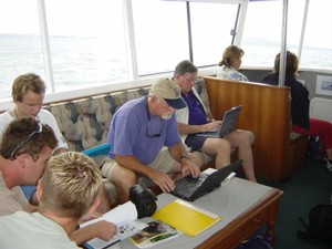 Bob Fisher (dark blue shirt) hard at work on the America’s Cup tender - Auckland 2003. The hardworking chap in the blue shirt is Angus Phillips correspondent for The Washington Post. photo copyright Larry Keating taken at  and featuring the  class