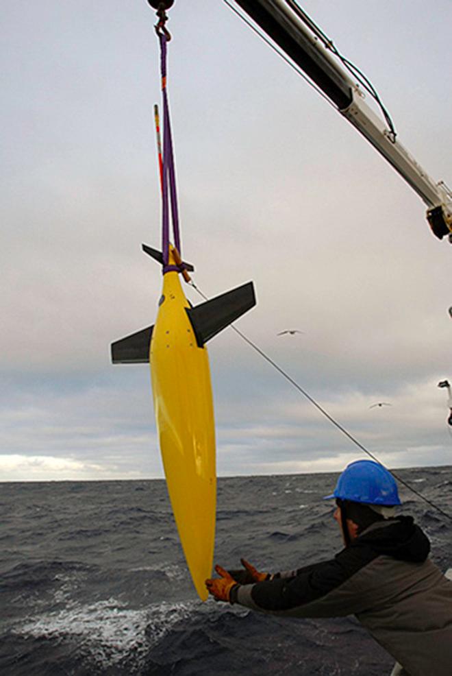 A SeaGlider is lowered from the research vessel. The robotic glider, which made repeated dives to depths of hundreds of meters, measured ocean properties then relayed them back to the scientists on board the ship.  (Courtesy of Eric Rehm, University of Washington) © WHOI