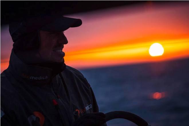 Leg 7 to Lisbon onboard Team Alvimedica. Day 07. Dave Swete smiles as the sun pokes out from underneath a thick layer of clouds,just before it dips below the horizon to begin another cold North Atlantic night. Nearing the centre of the Azores High the fleet scatters north-to-south while conditions become light and difficult. - Volvo Ocean Race 2015 ©  Amory Ross / Team Alvimedica