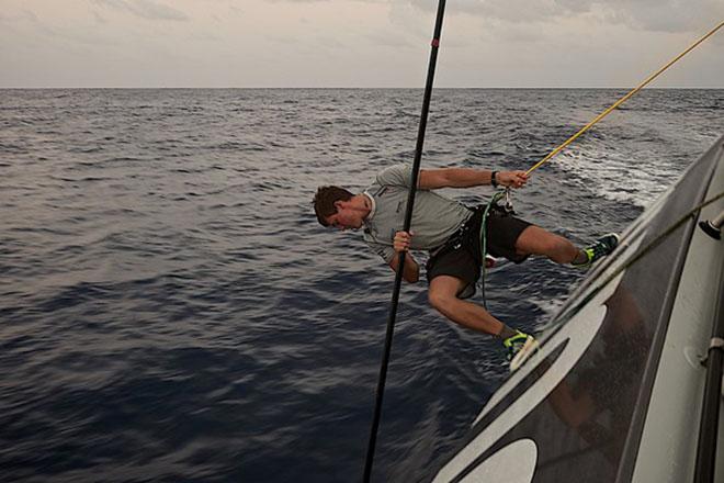 Leg 6 to Newport onboard Team Brunel. Day 12. Rokas Milevicius tries to get weed from the keel with a sail batten,the sargasso weed is still playing a big roll in the drag race.  © Stefan Coppers/Team Brunel