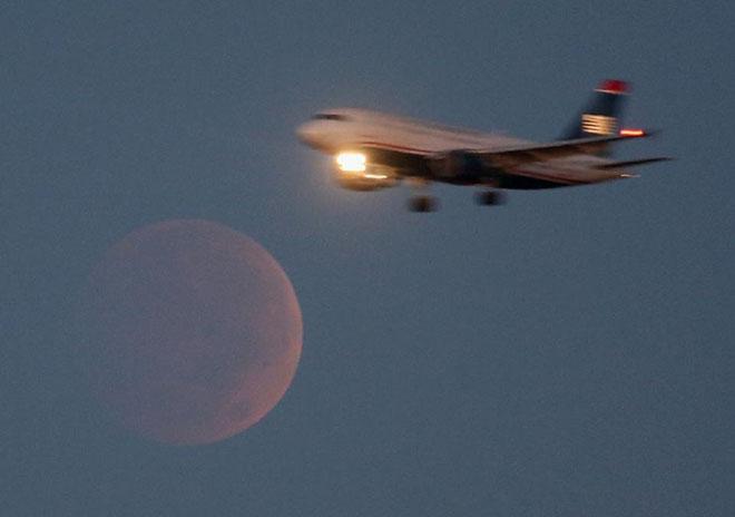 A commercial airliner approaches Reagan National Airport in Washington, DC, as it flies past the full moon during a lunar eclipse on October 8, 2014 © Mark Wilson http://www.bigshotz.com.au