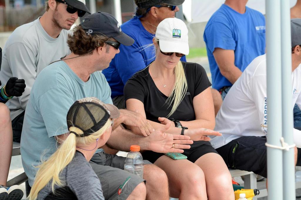 The USA’s Dave Perry (left facing) talks tactics with Canada’s Elizabeth Shaw while Shaw’s crew, Antilles School junior sailor, Paige Clarke (lower left), from St. John, looks on.  Credit: Dean Barnes  © Dean Barnes