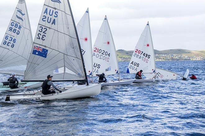 Laser dinghies line up start, except for one who is capsized. © Jimmy Emms