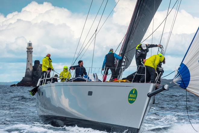 The crew of Aragon have no time to admire the Fastnet Rock as they clear the foredeck after a sail change – Rolex Fastnet Race © Quinag