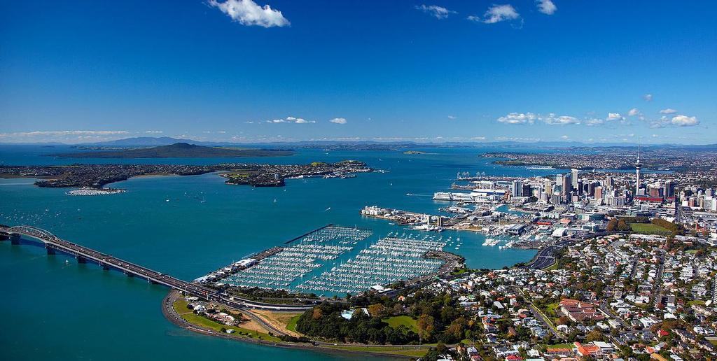 Auckland and the Waitemata Harbour. The Harbour Bridge to the North Shore is in the foreground. Behind that is the Westhaven marina with the Royal New Zealand Yacht Squadron.  The America’s Cup is expected to be raced to the left of Rangitoto Island in the far background. © SW