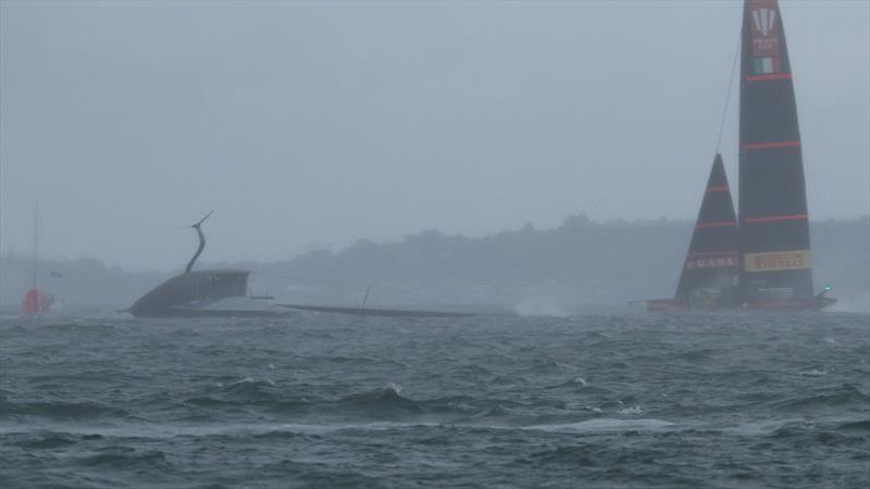 Luna Rossa sails past American Magic, in the rain squall, as Patriot's mast hits the water after capsizing at 47kts - Hauraki Gulf - January 17, 2021 - Prada Cup - 36th America's Cup photo copyright Richard Gladwell - Sail-World.com / nz taken at New York Yacht Club and featuring the AC75 class