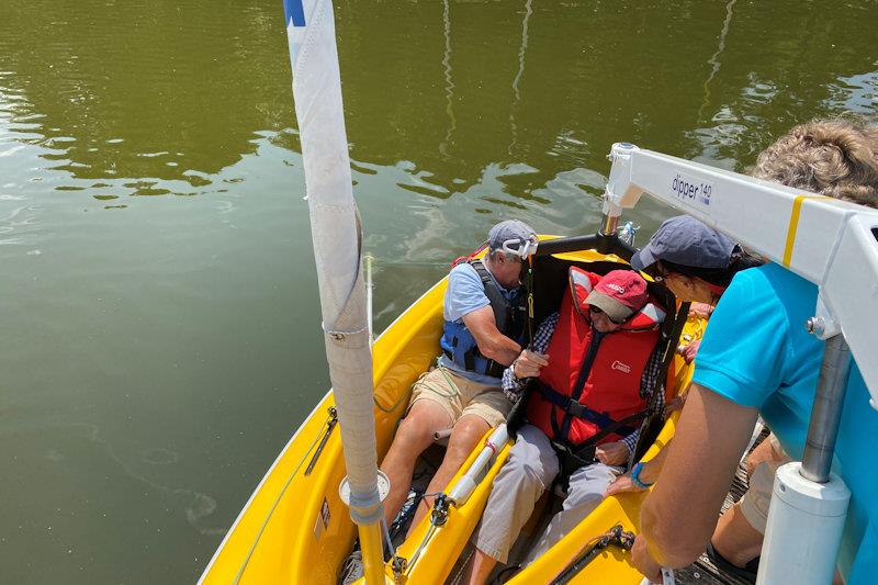 Hoist process step 5 - just before touchdown, hold any cushions in place, as supporting a person well makes a massive difference to their ability to enjoy the sail (cushions can be wedge-shaped or very flat) photo copyright Magnus Smith taken at Frensham Pond Sailability and featuring the Hansa class