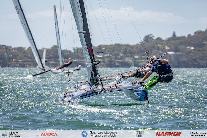 Australian A-Cat Nationals on Lake Macquarie Day 5 - Dom Tanner demonstrates his flexibility on his lovely blue DNA F1x photo copyright Gordon Upton / www.guppypix.com taken at South Lake Macquarie Amateur Sailing Club and featuring the A Class Catamaran class