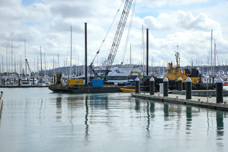 Construction barge moves past new superyacht berths - America's Cup Base development - Auckland - Wynyard Edge Alliance - July 25, 2019 photo copyright Richard Gladwell, Sail World NZ taken at Royal New Zealand Yacht Squadron and featuring the ACC class