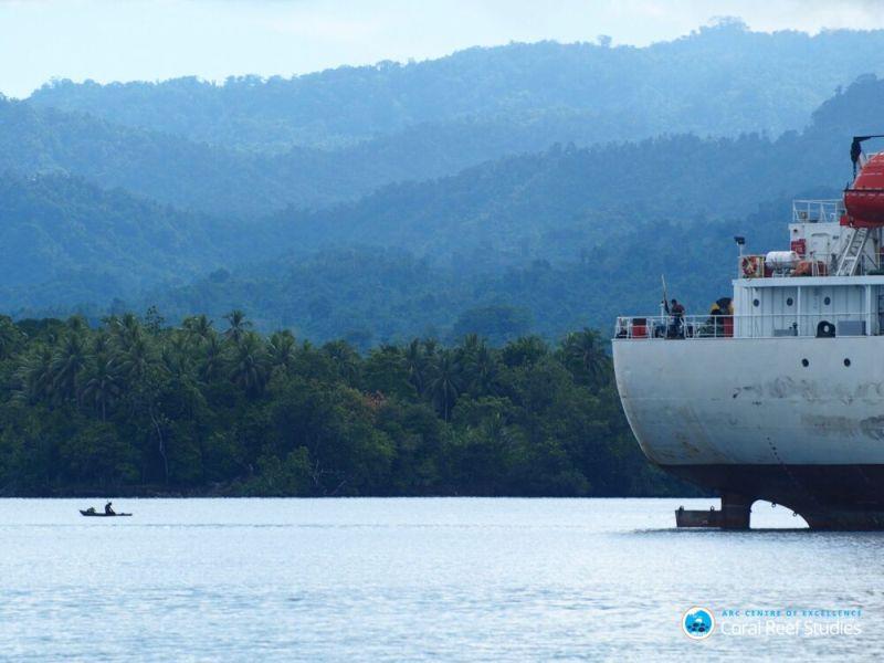 A local fisher waits for fish in his dugout canoe, while an industrial tuna ship glides by En-route to Wadau village, Karkar Island, Madang, Papua New Guinea photo copyright ARC CoE for Coral Reef Studies / Jacqueline Lau taken at  and featuring the Cruising Yacht class