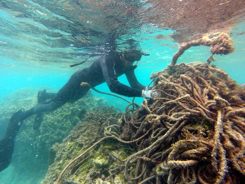 A marine debris diver carefully cuts a derelict fishing net to remove it from the shallow coral reef at Pearl and Hermes Atoll, Northwestern Hawaiian Islands - photo © NOAA Fisheries