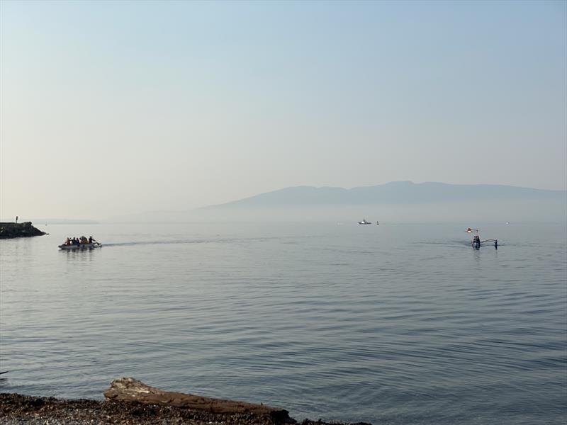 Outrigger canoes and other marine traffic ply the waters of Bellingham Bay during a 'low-smoke day' in mid-October; the `fog` in the background used to be trees photo copyright David Schmidt taken at Bellingham Yacht Club and featuring the Environment class