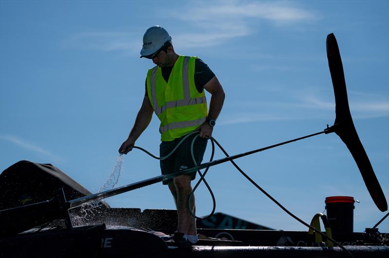 A crew member cleans a F50 catamaran at the Technical Base after a practice session ahead of the Great Britain Sail Grand Prix | Plymouth in Plymouth, England. 29th July 2022 - photo © Jon Super/SailGP