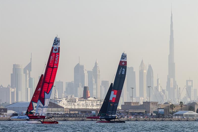 Canada SailGP Team helmed by Phil Robertson and Switzerland SailGP Team helmed by Sebastien Schneiter sail past the Burj Khalifa and Waterfront Platinum Area on Race Day 1 of the Dubai Sail Grand Prix photo copyright Felix Diemer for SailGP taken at  and featuring the F50 class