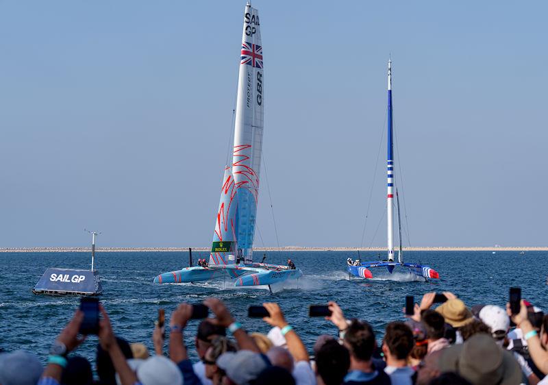 Spectators watch on as Great Britain SailGP Team helmed by Ben Ainslie and France SailGP Team helmed by Quentin Delapierre sail closely past the Race Village on Race Day 2 of the Dubai Sail Grand Prix presented by P&O Marinas photo copyright Joe Toth for SailGP taken at  and featuring the F50 class