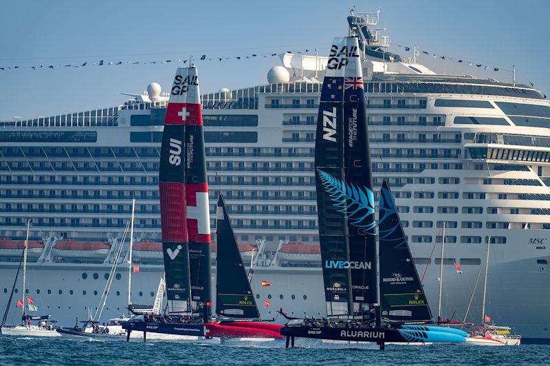 New Zealand SailGP Team helmed by Peter Burling and Switzerland SailGP Team helmed by Sebastien Schneiter go past a cruise ship on Race Day 1 of the Emirates Sail Grand Prix presented by P&O Marinas in Dubai, United Arab Emirates - photo © Bob Martin for SailGP