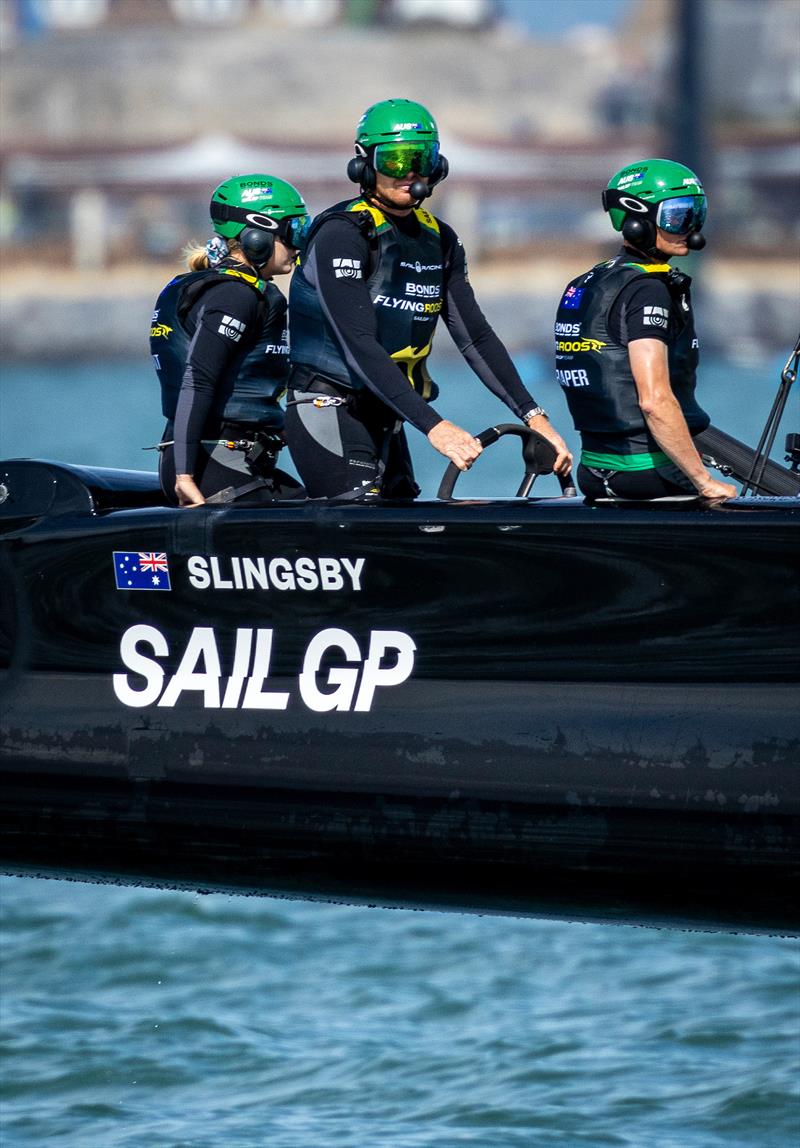 Tom Slingsby, driver of BONDS Flying Roos SailGP Team, takes the wheel of the F50 catamaran alongside Chris Draper, wing trimmer of BONDS Flying Roos SailGP Team, during a practice session ahead of the Emirates Great Britain Sail Grand Prix photo copyright Felix Diemer for SailGP taken at  and featuring the F50 class