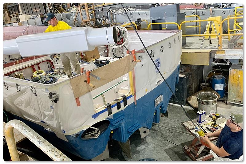 Mechanic Brailler Silva (blue shirt) utilizes an electric overhead hoist to transport the composite component - photo © Viking Yachts