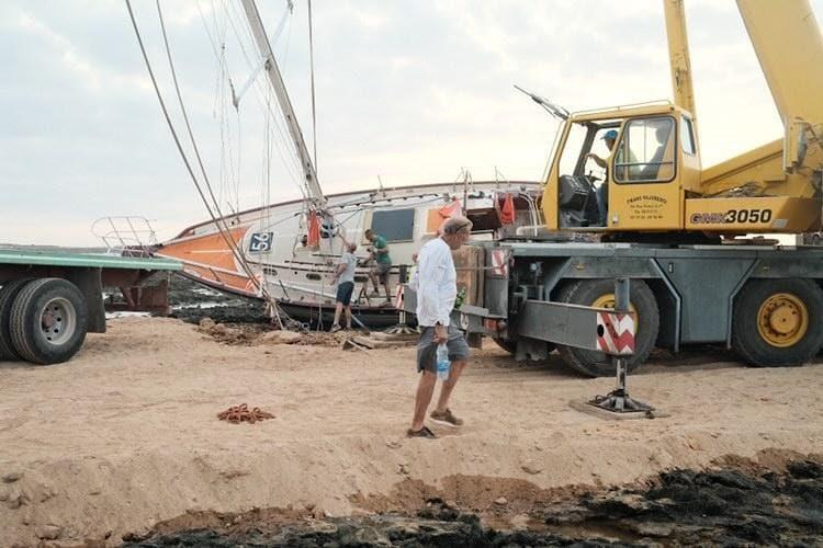 Guy deBoer's walks in front of Spirit, now off the beach and in the yard in Fuerteventura, ready for repairs and re-launching - photo © Laerke from Mara Noka!