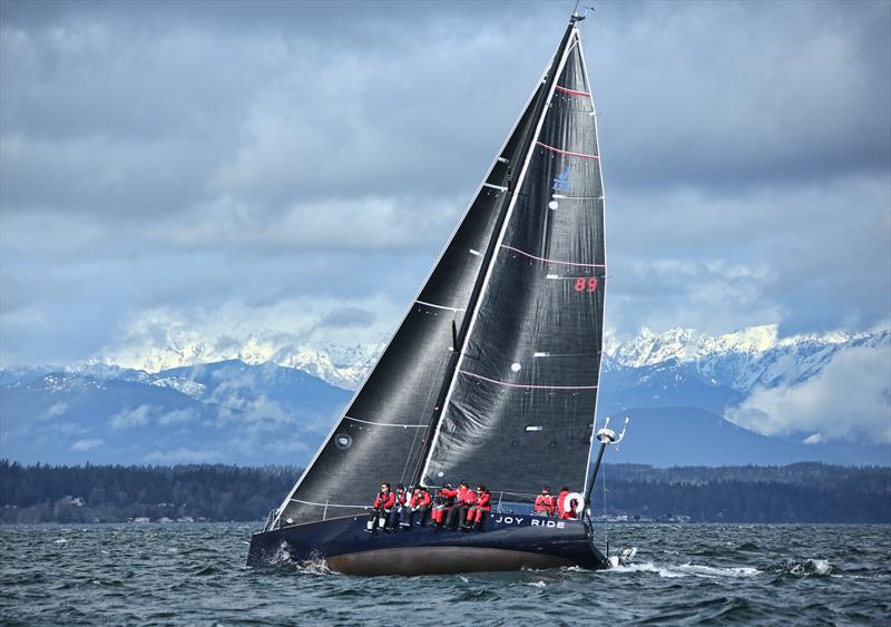 Joy Ride flashes her undercarriage as Washington State's Olympic Mountains flash their snowy slopes through the clouds - photo © Jan's Marine Photography