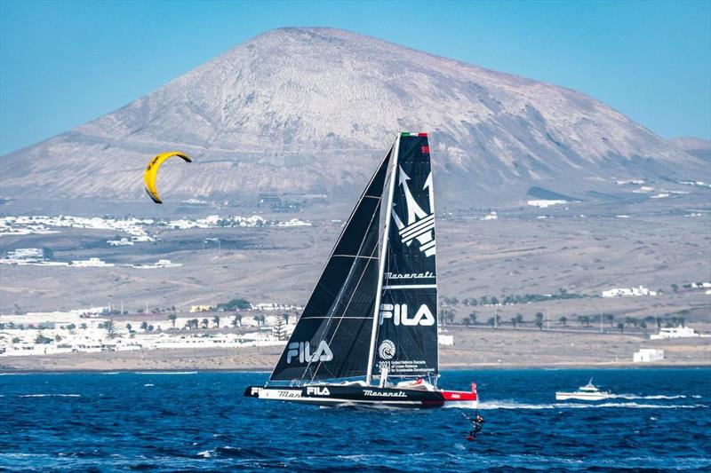 Speed machines: Giovanni Soldini's Multi 70 Maserati and a local kite surfer enjoy the breezy conditions at the start of the RORC Transatlantic Race photo copyright Lanzarote Photo Sport taken at Royal Ocean Racing Club and featuring the MOD70 class