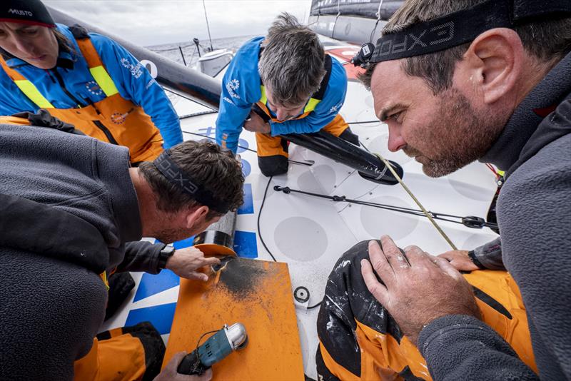 The Ocean Race 2022-23 Leg 3, Day 9 onboard 11th Hour Racing Team. The team watches as the outer layers of carbon are ground away, displaying the true extent of the cracks - photo © Amory Ross / 11th Hour Racing / The Ocean Race