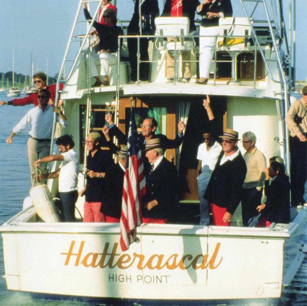 Watching Liberty leave, New York YC Commodore Robert Stone cheers with hands upraised, Commodore Bob McCullogh signals 