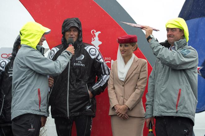 Emirates Team New Zealand Skipper Dean Barker interviewed on stage by Andy green while Tucker Thompson shades an Emirates cabin crew member from the rain during the dock out show. Its raining in San Francisco ahead of racing on day eleven of America’s Cup 34. 21/9/2013 © Chris Cameron/ETNZ http://www.chriscameron.co.nz