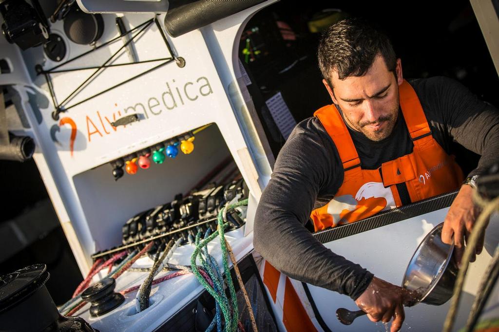 October, 2014. Leg 1 onboard Team Alvimedica. Day 8. Day of the Cape Verdes transit and decision time for the Equator / Doldrums approach. Mark Towill cleans his breakfast dish in the ocean water on the deck. ©  Amory Ross / Team Alvimedica