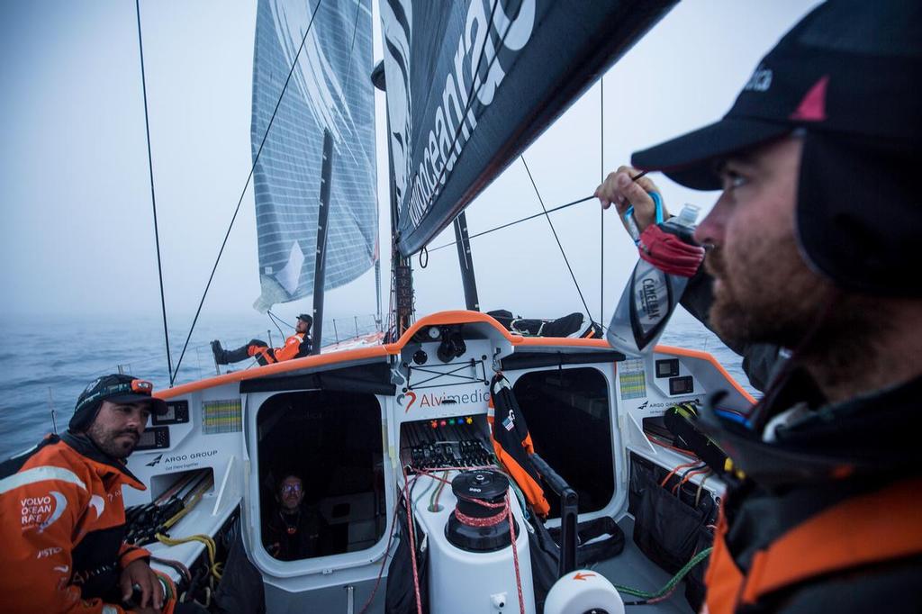 October, 2014. Leg 1 onboard Team Alvimedica. Day 21. Winds lighten and the complicated road to Cape Town begins as the first High pressure system rolls through the fleet. Skipper Charlie Enright (R) delivers the bad news from the latest position report to the rest of the on-deck watch, Mark Towill (L) and Dave Swete (M) ©  Amory Ross / Team Alvimedica