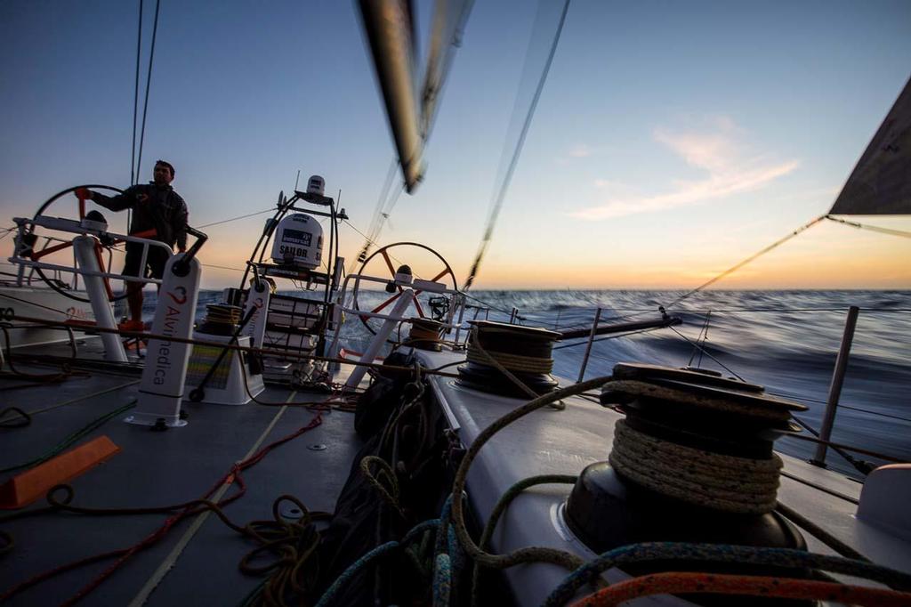 2014-15 Volvo Ocean Race. Leg 1 onboard Team Alvimedica. Day 4. It's a drag race to the Canary Islands with the fleet very compressed along the NW coast of Africa. Skipper Charlie Enright alone at the back of the boat as the rest of the on-deck watch occupy the bow to keep weight forward in light winds at sunrise. &copy;  Amory Ross / Team Alvimedica