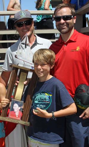 TJ O'Rourke of Dana Point Yacht Club proudly holds the Jessica Uniack Memorial Beach to Bay Race perpetual trophy after finishing first in the Sabot C3 class in the 2014 Beach to Bay Race. Long Beach Yacht Club Sailing Director Jess Gerry (left) and son of Jessica Uniack, Alex Uniack (right), congratulate TJ on his win. The trophy is traditionally awarded to the first place finisher in the largest class. photo copyright Rick Roberts taken at  and featuring the  class