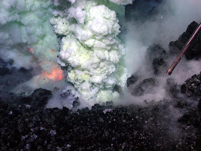 The orange glow of magma is visible on the left of the sulfur-laden plume. The area shown in this image is approximately six feet across in an eruptive area approximately the length of a football field that runs along the summit. © Woods Hole Oceanographic Institution (WHOI) http://www.whoi.edu/