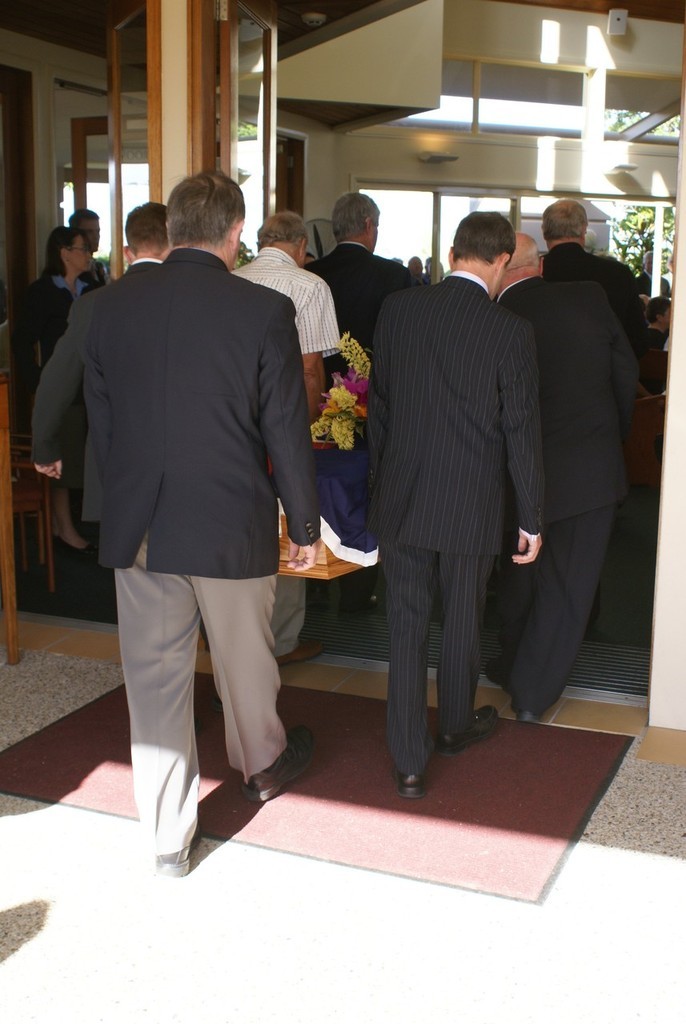 Pallbearers, including sons John Jnr and Greg and brother Garry, carry the Australian flag-draped casket into the chapel. - John Haines funeral © Bob Wonders