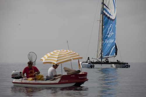Calm conditions before racing on day 1 of the Extreme Sailing Series™ Almeria, with The Wave, Muscat drifting past a local fishing boat. © Lloyd Images http://lloydimagesgallery.photoshelter.com/