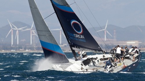 TeamOrigin TP52 on the final day of the Audi MedCup 2010. The team which stood for raising awareness of climate change heads fittingly into a backdrop of wind-turbines off the Italian coast © Ian Roman/TEAMORIGIN www.ianroman.com