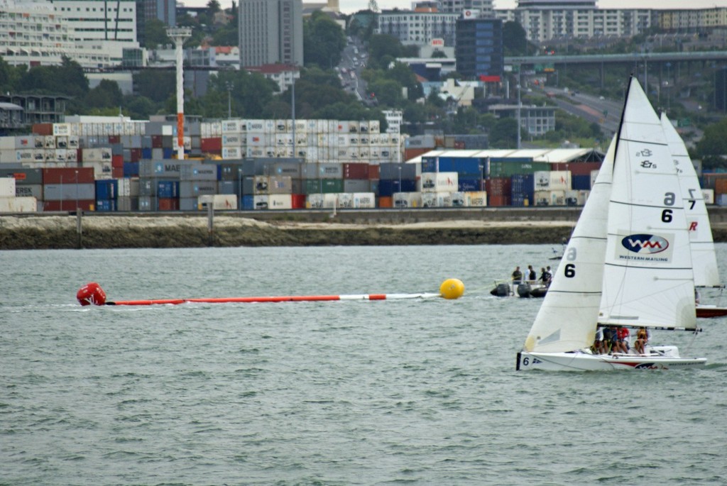 Supported by buoys TVS’s wingmast is towed home by Team NZ’s tender © SW